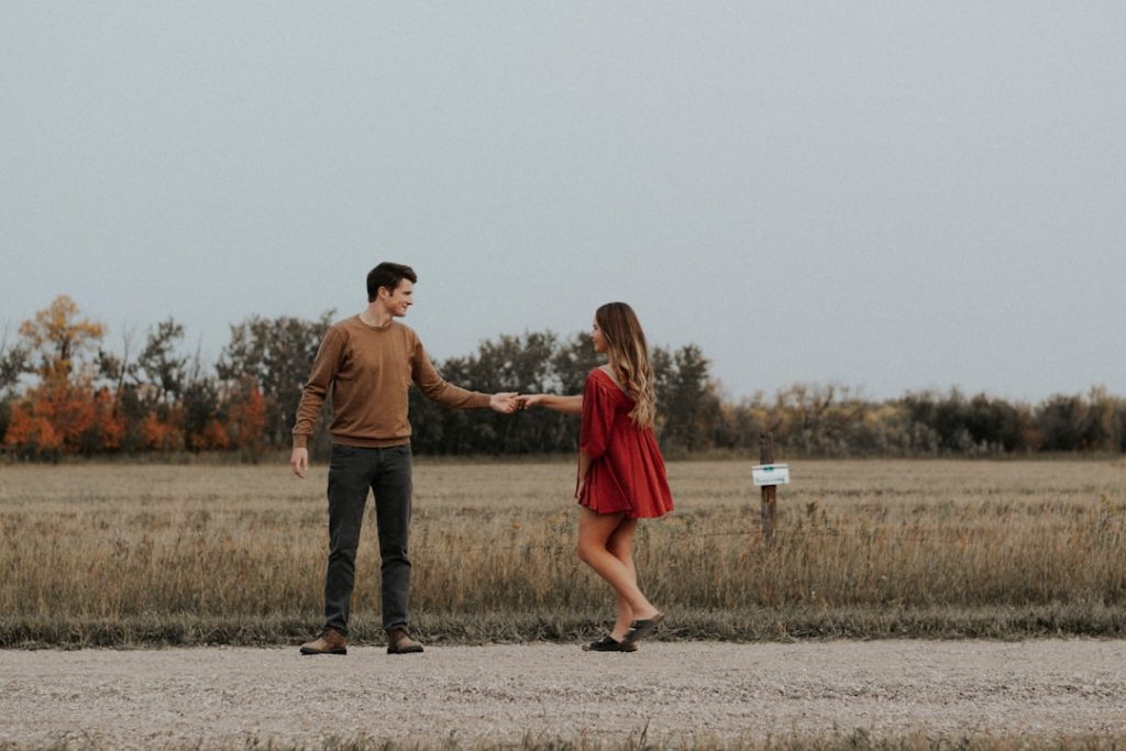 "A couple walking on a dirt road together but apart"