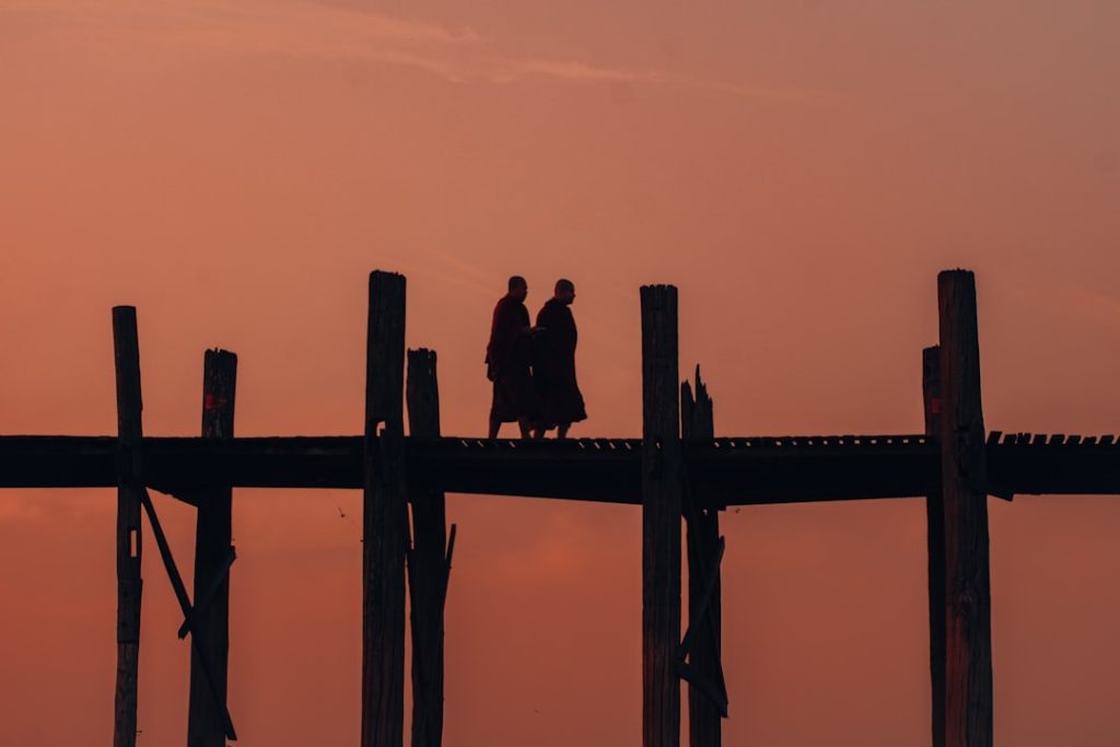 "Silhouette of a couple standing on a bridge at sunset"