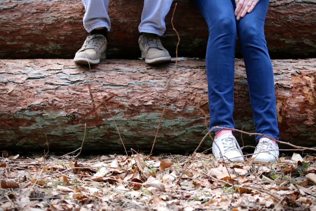 "Two people sitting on a log in the woods"