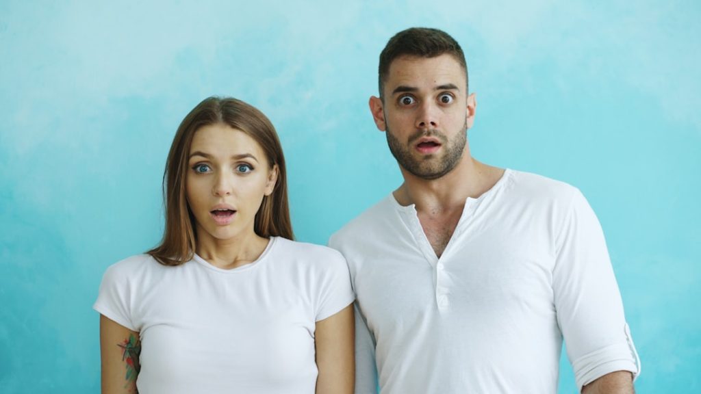 Couple with shocked expressions against blue background