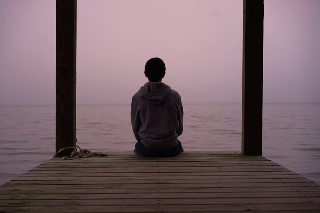 person sitting on dock above body of water
