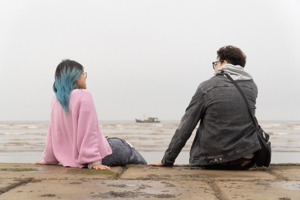 "Couple sitting in silence on pier"